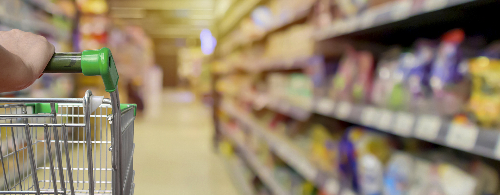 A shopping cart being pushed down the aisle of a grocery store.