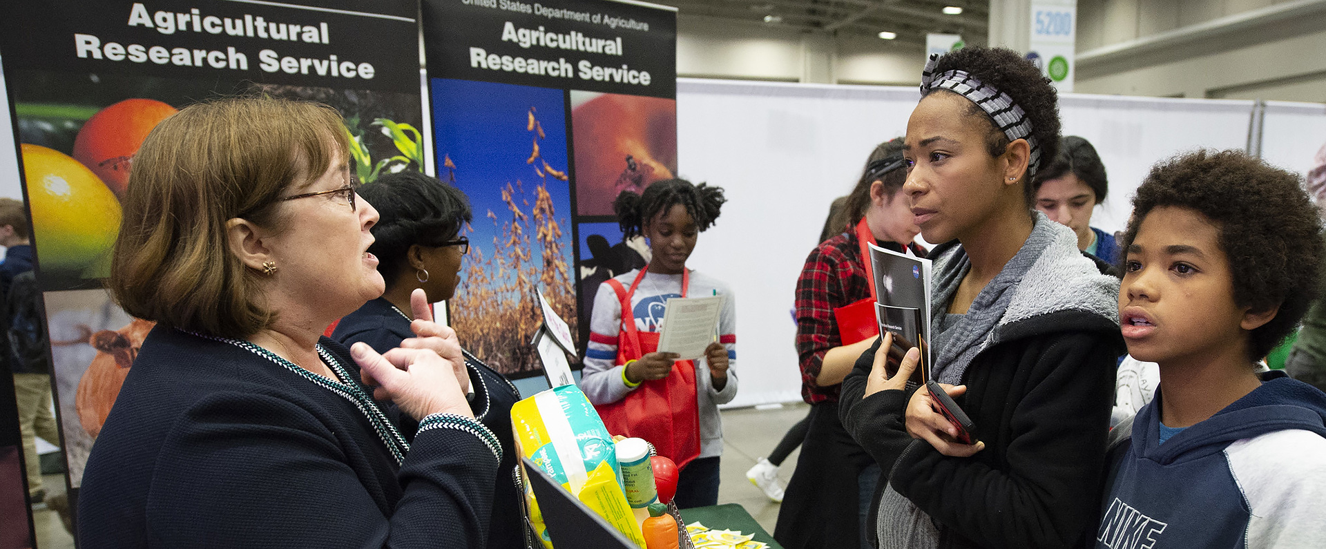 An ARS employee talking to students at an outreach event