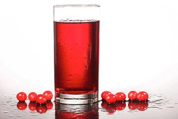 Cranberries next to a glass of cranberry juice. 