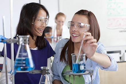 Female high school students performing experiment in chemistry lab