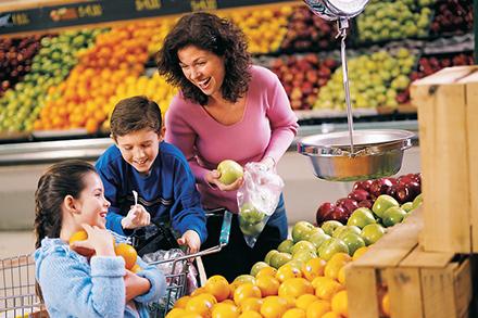 A woman, a boy and a girl shopping for produce. 