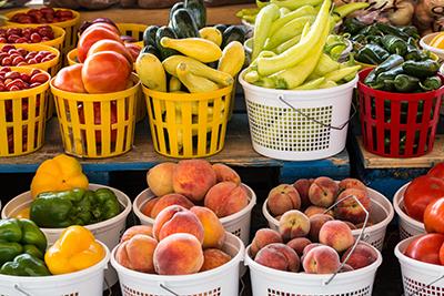 Baskets of tomatoes, pepers, peaches and squash