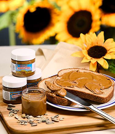 Sunbutter spread on a piece of bread and jars of Sunbutter next to it.  