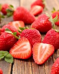 Sliced fresh strawberries laying on a wooden board