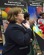 An ARS employee talking to students at an outreach event