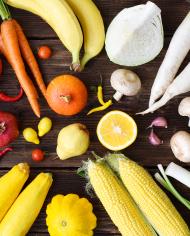 White, yellow, green, orange, red, purple fruits and vegetables on wooden background. 