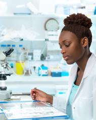 Woman in a white lab coat looking at a document in a laboratory