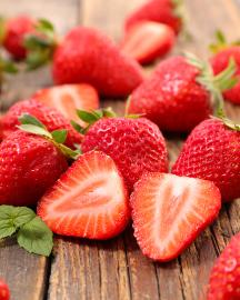 Sliced fresh strawberries laying on a wooden board
